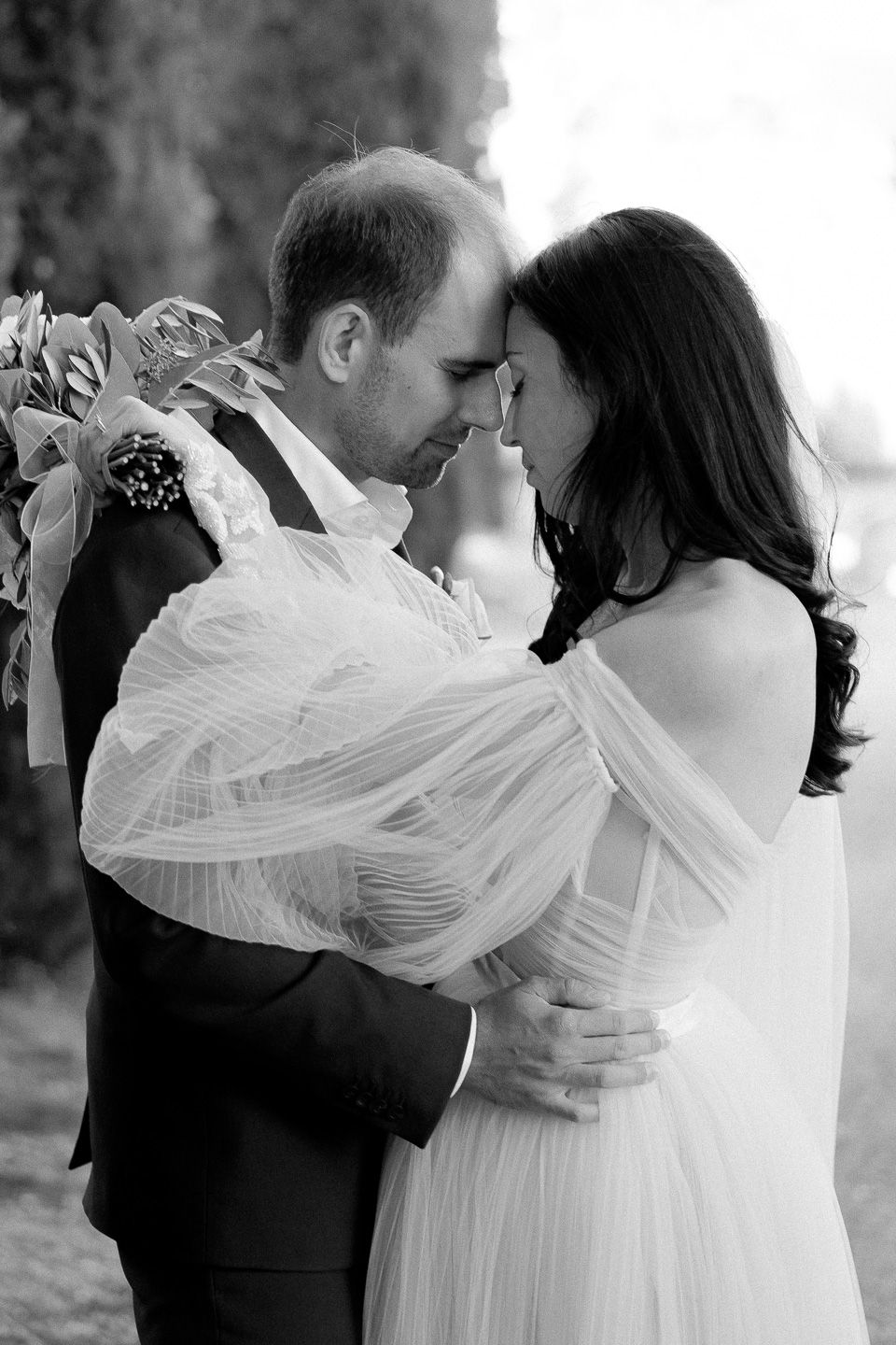 bride and groom resting their foreheads together with eyes closed. The bride is wearing a off-the-shoulder wedding dress from Galia Lahav