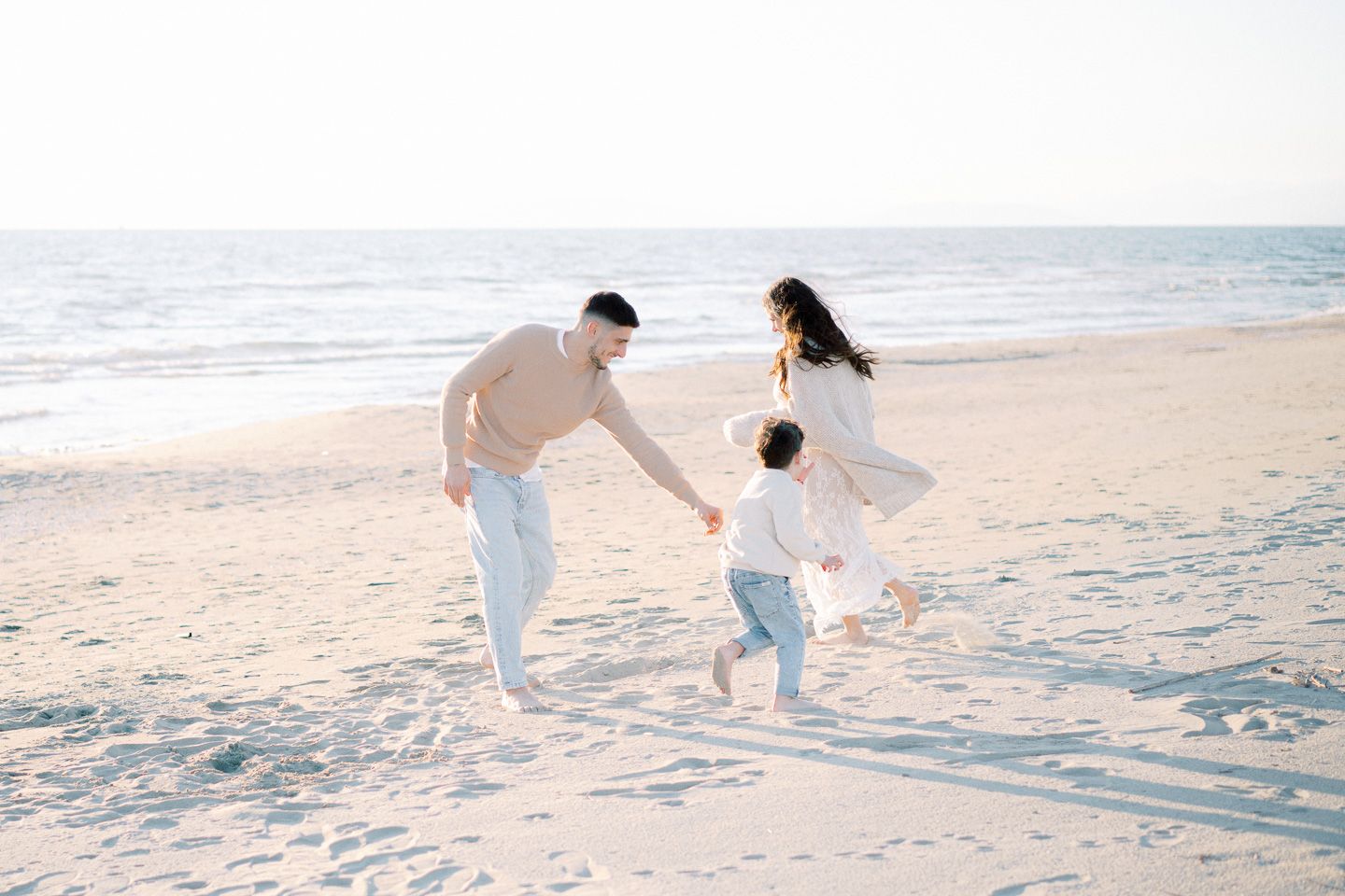 Mother and father playing tag with their son during a family lifestyle photoshoot, Tuscan beach of Versilia