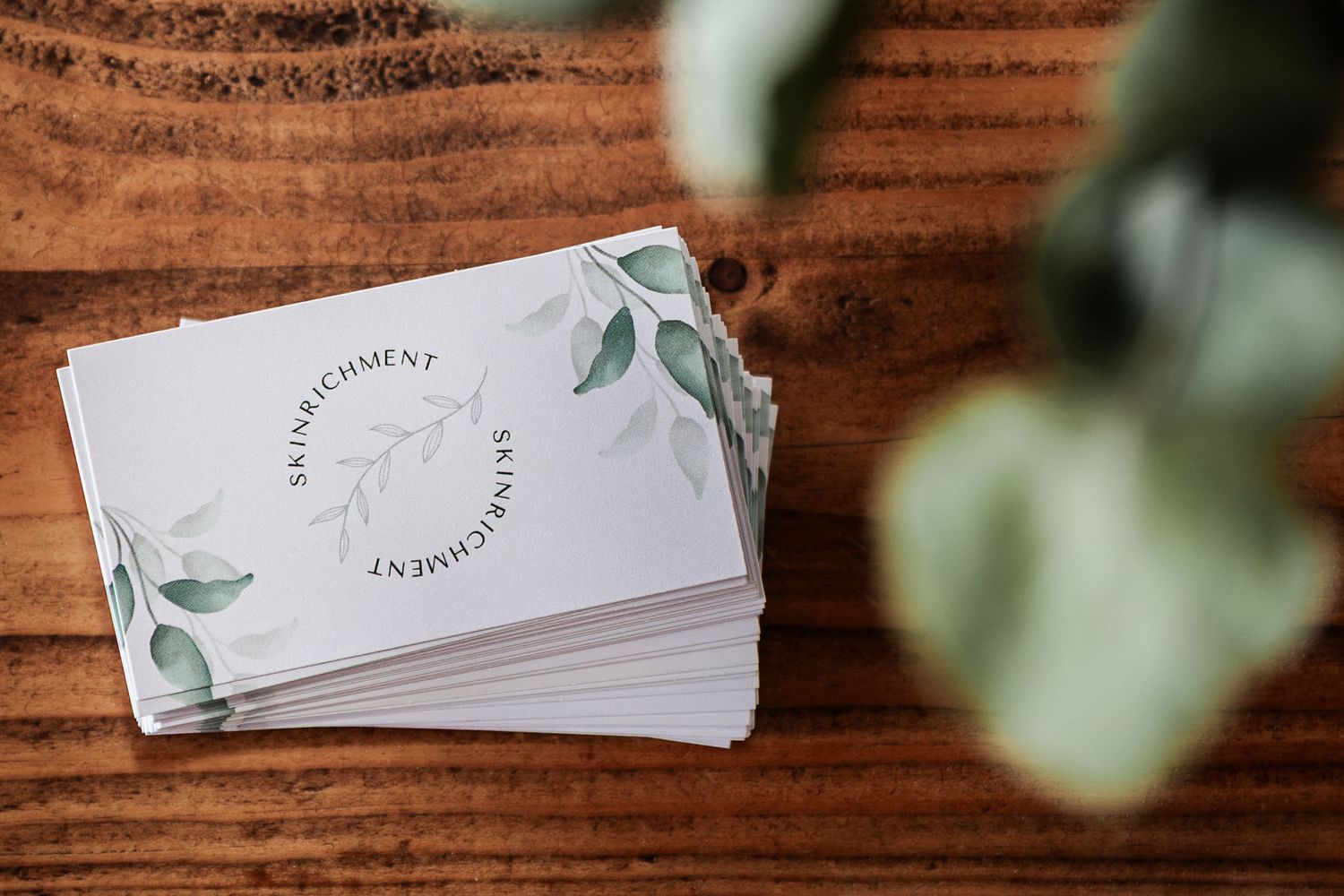 A stack of business cards sit on a wooden desk. Taken at a  Bristol personal brand photoshoot for Skinrichment, a Clifton skin therapist
