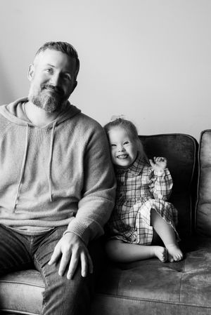 Black and white photo series showing tender moments between a parent and child relaxing together on a couch.