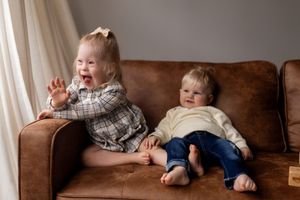 Candid lifestyle moment of family members relaxing on leather sofa in neutral toned room.