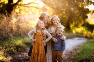 Family walking together on a sunlit path through nature during golden hour sunset.