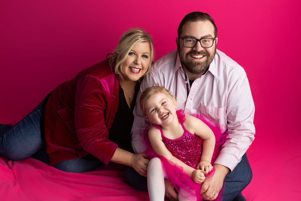 A series of playful family portraits against a vibrant pink backdrop showing joyful interactions and laughter.