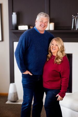 A couple wearing blue and red sweaters share joyful moments in a series of candid indoor photos.