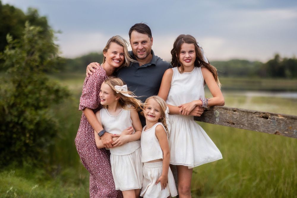 Family enjoying outdoor photo session in grassy field during golden hour.