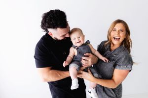 Happy family moment with parents holding baby against white background.