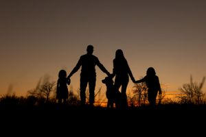 Silhouettes of a family walking together against a dramatic sunset sky.