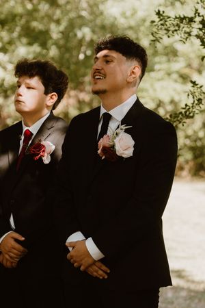 Groomsmen in black suits and red ties share laughs during wedding photos.