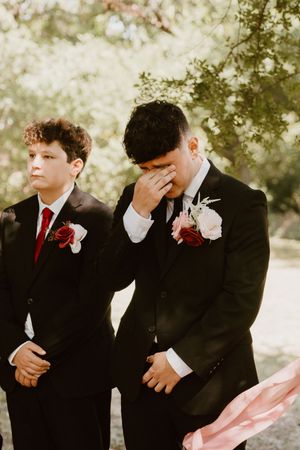 Young groomsmen in formal attire share candid moments during wedding photography.