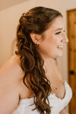 Side profile showing elegant curled hairstyle and white wedding dress.