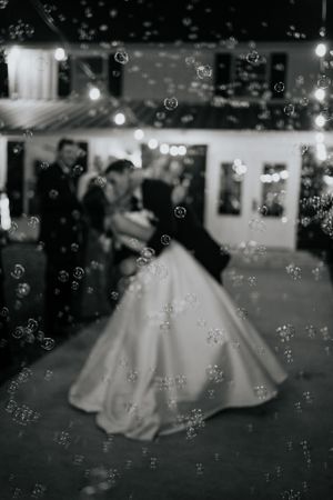 A couple dances together during their first dance at a wedding reception with bubbles floating in the air.
