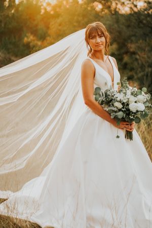 Flowing white wedding dress with long train photographed during golden hour.