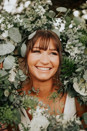 Close-up portrait through white floral arrangements and greenery.