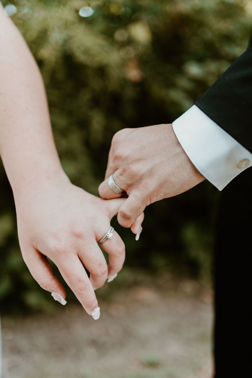 Close-up of newlywed couple's hands with wedding rings against blurred background.