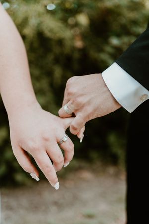 Close-up of newlywed couple's hands with wedding rings against blurred background.
