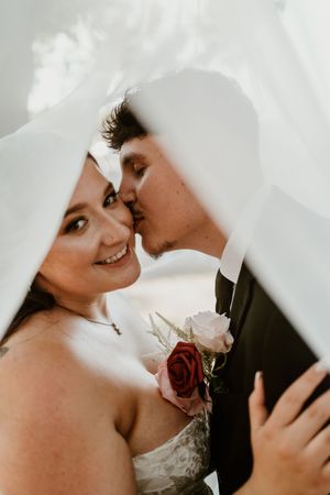 Romantic close-up shot of a couple sharing an intimate moment with white roses and formal attire.