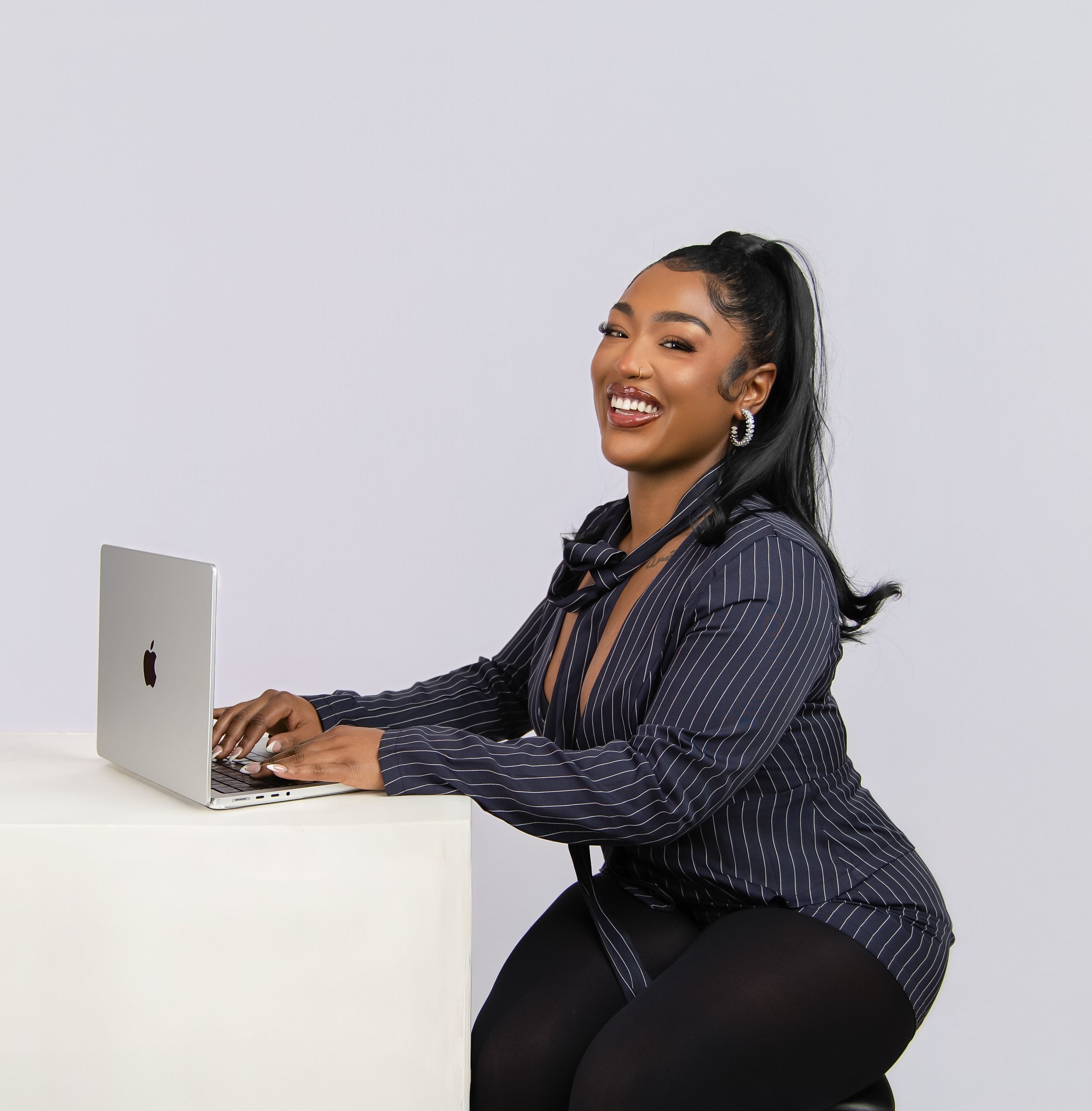 Professional in black business attire working on laptop computer while striking different poses against white background.