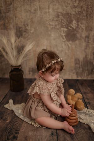 Rustic baby photoshoot in NYC, styled with a vintage backdrop, basket of bread, and warm earthy tones for a timeless portrait.