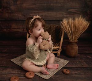 Rustic milestone baby portrait in NYC, with vintage props, wheat accents, and a cuddly bunny toy.