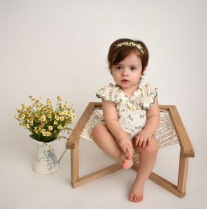 Bright and airy milestone baby portrait in Brooklyn, NY, featuring a little girl in a floral romper with fresh flowers for a spring-inspired