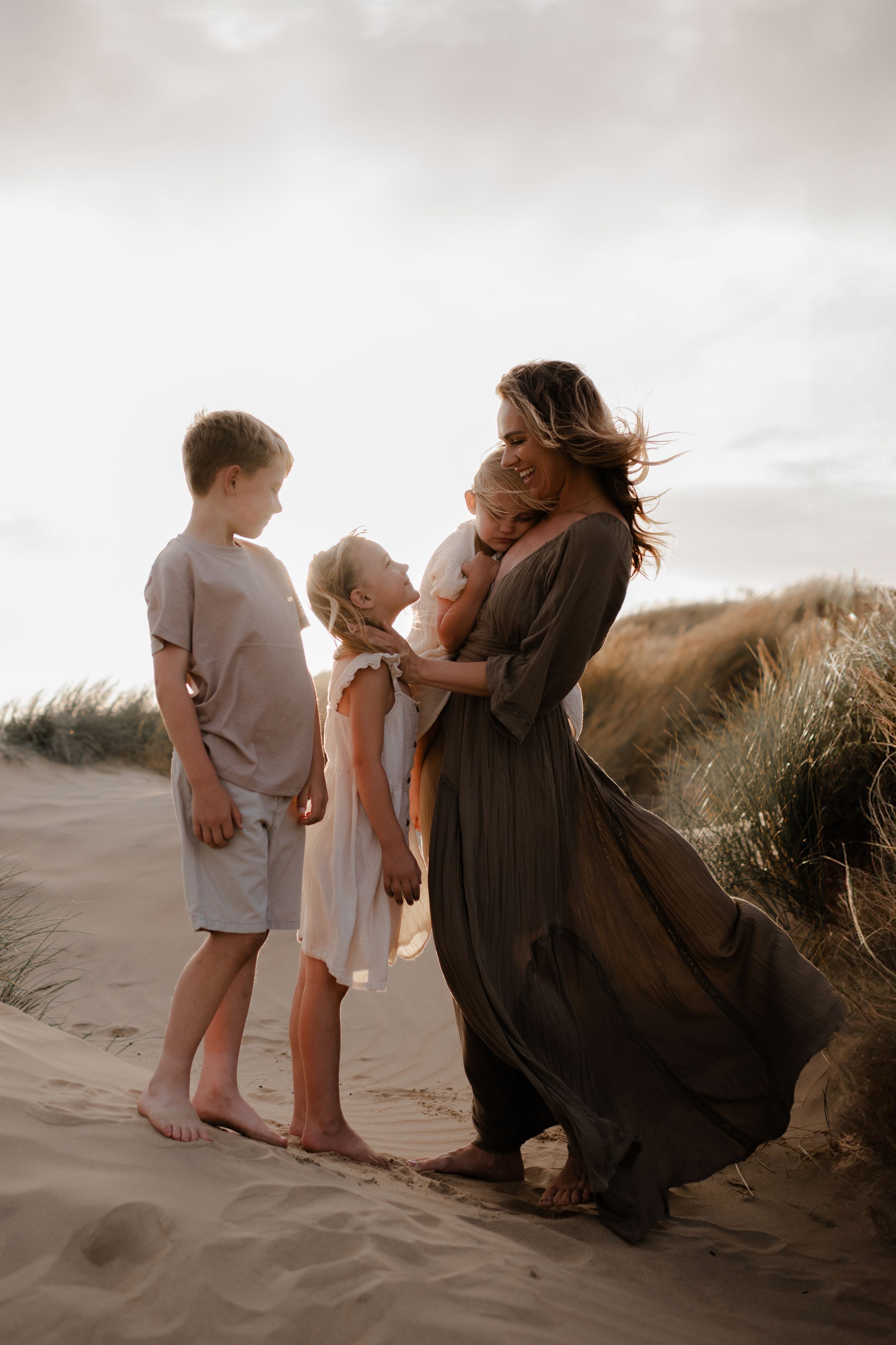 a mother looking at her children at sunset on the beach during a family photo session