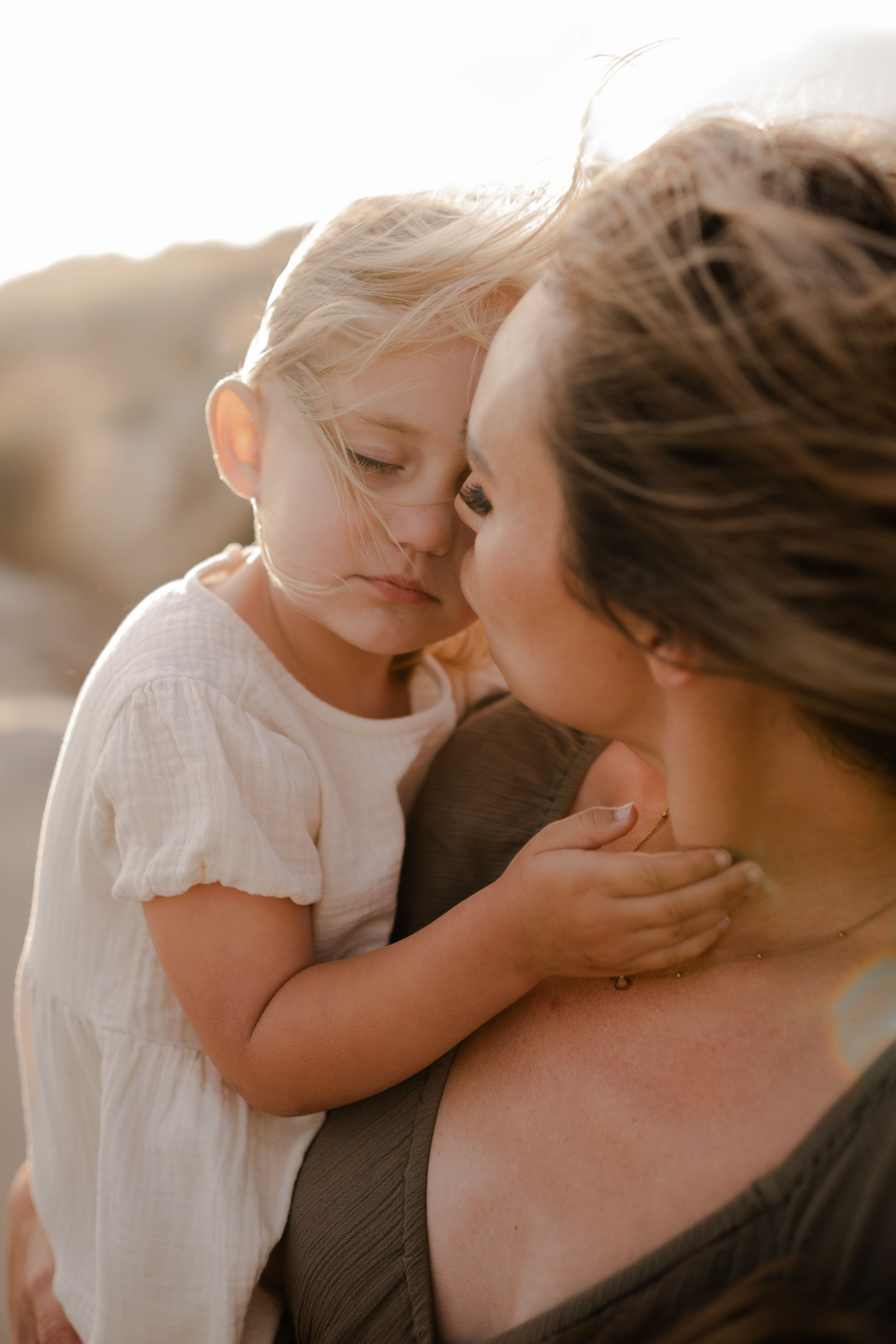 a little girl touching her mother's face and closing her eyes
