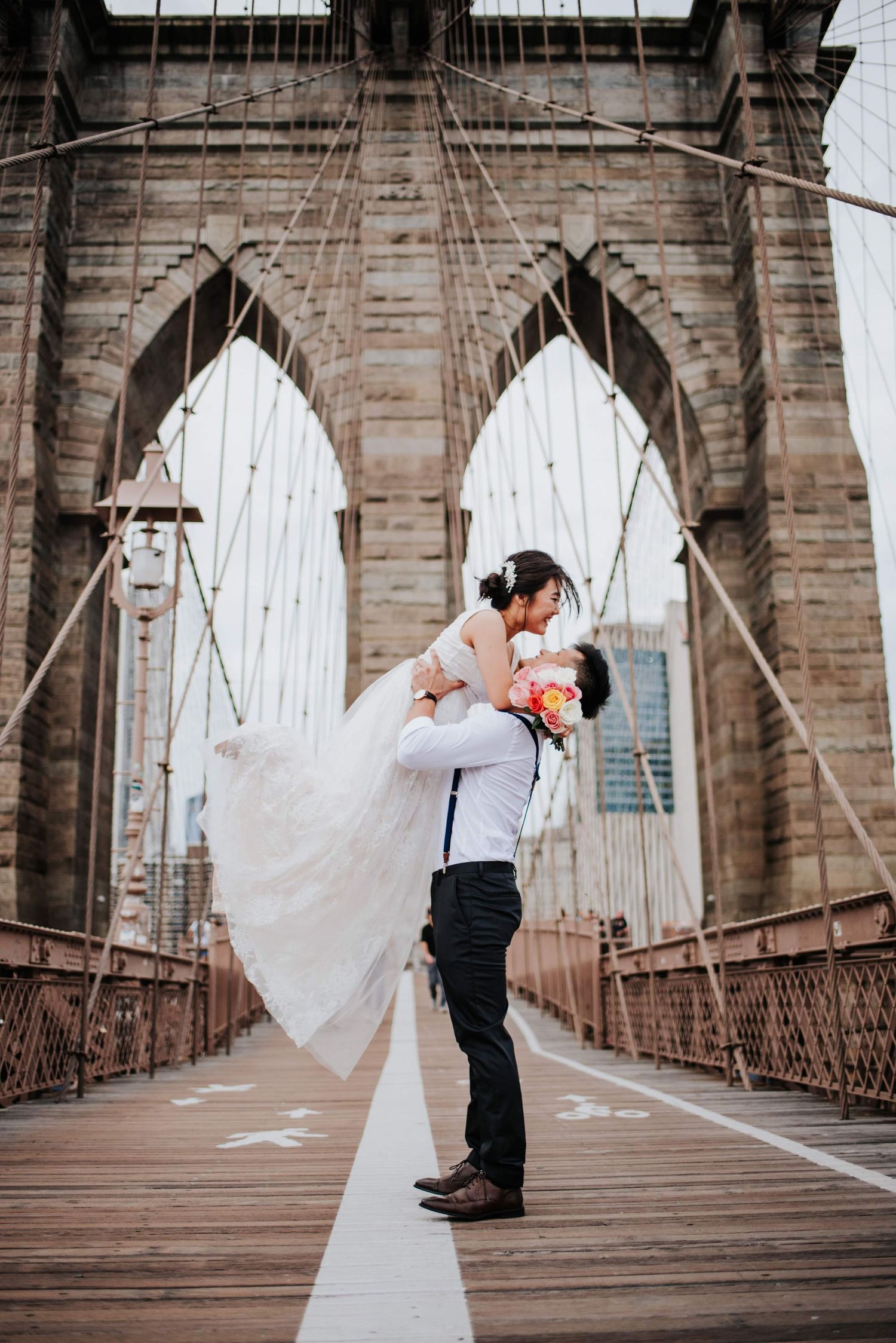 Wedding sequence on Brooklyn Bridge showing flowing white dress against architectural backdrop.