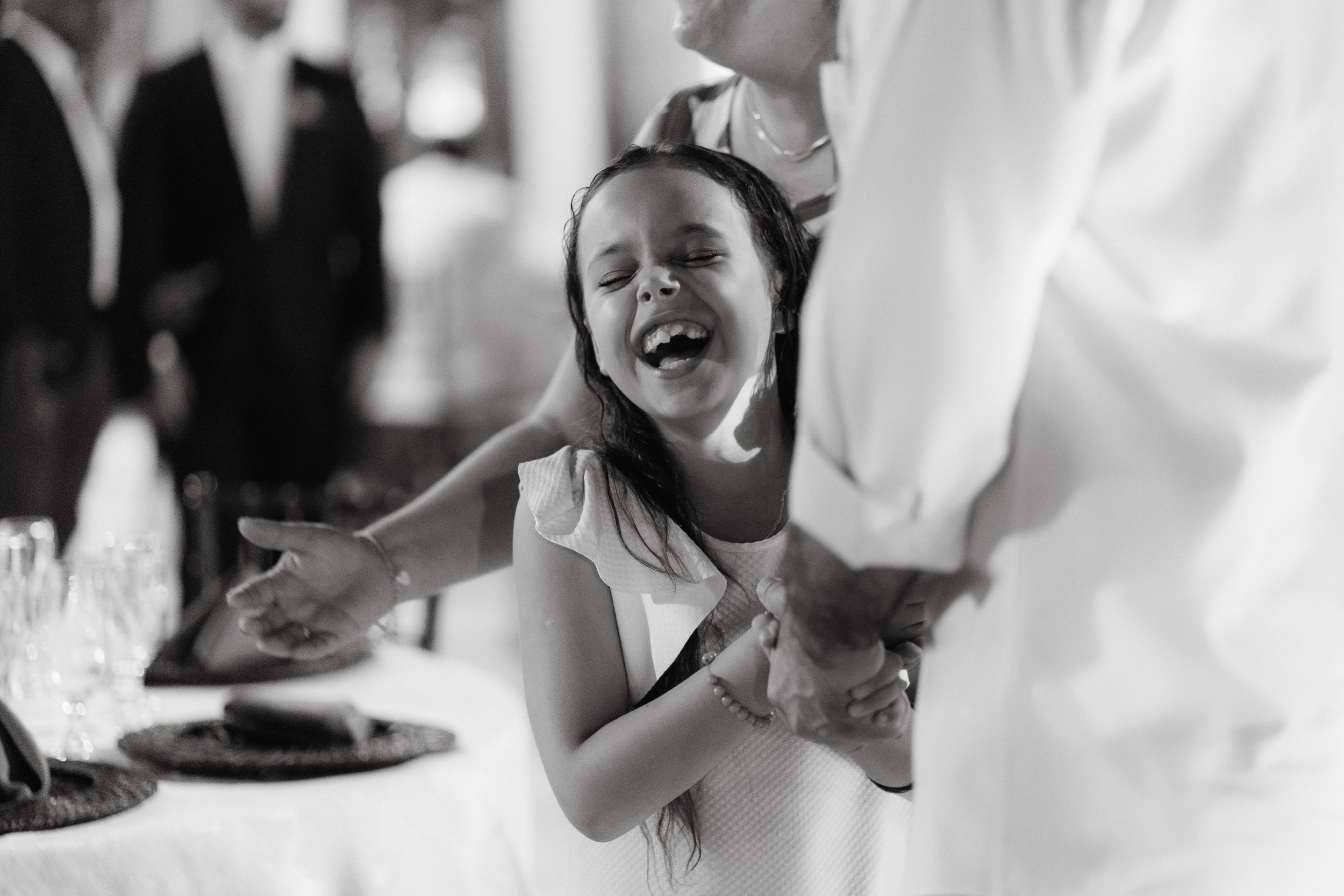 A candid black and white moment of pure joy captured during a wedding reception.