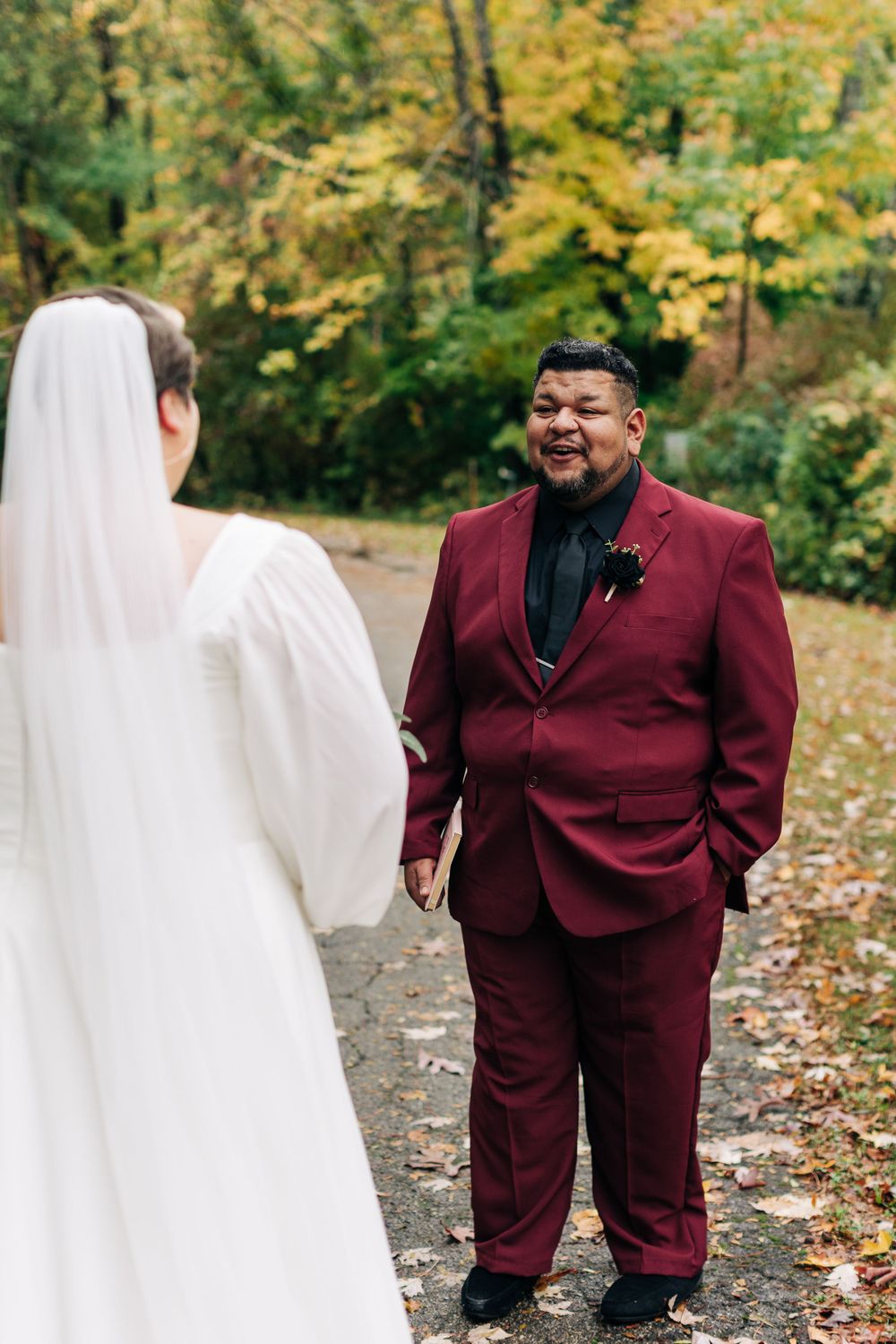 A wedding ceremony moment captured on a fall path with golden leaves and trees.