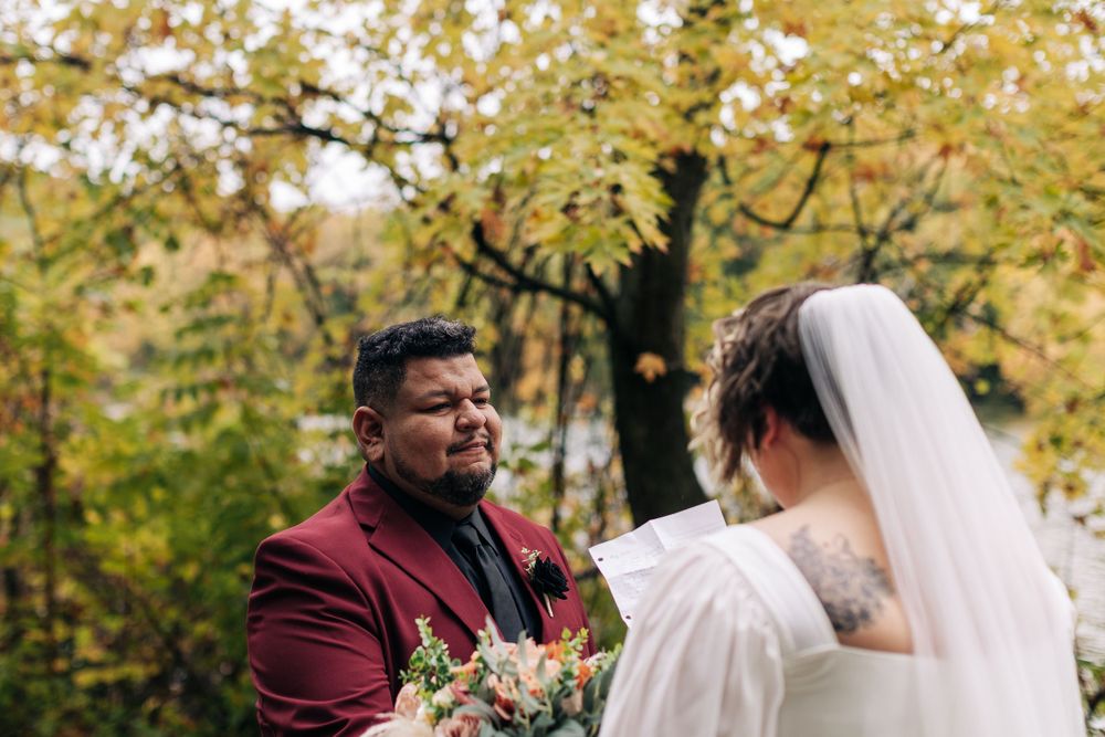 An intimate wedding moment captured during an autumn ceremony by the water.