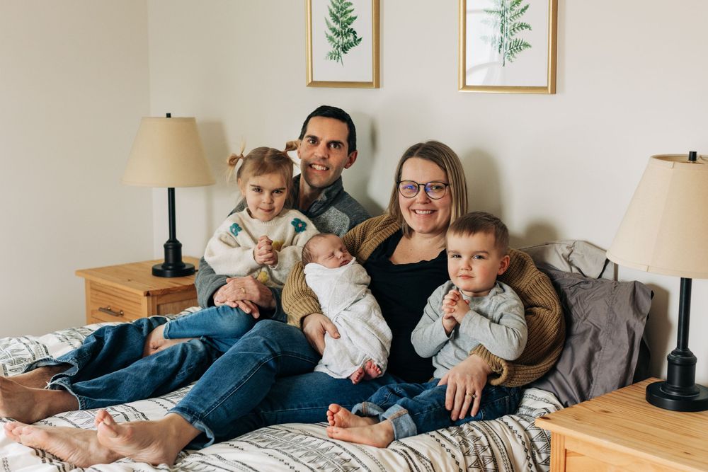 Family relaxing together on a bed with botanical prints on the wall.