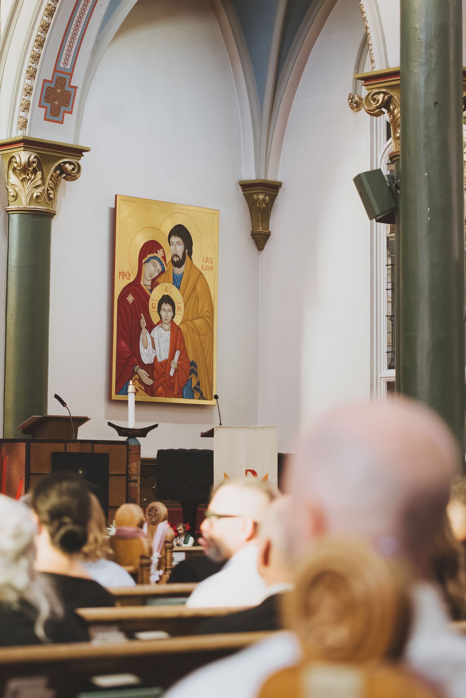 parishioners sitting in the pews with a byzantine painting of the holy family can be seen in the background at st andrew
