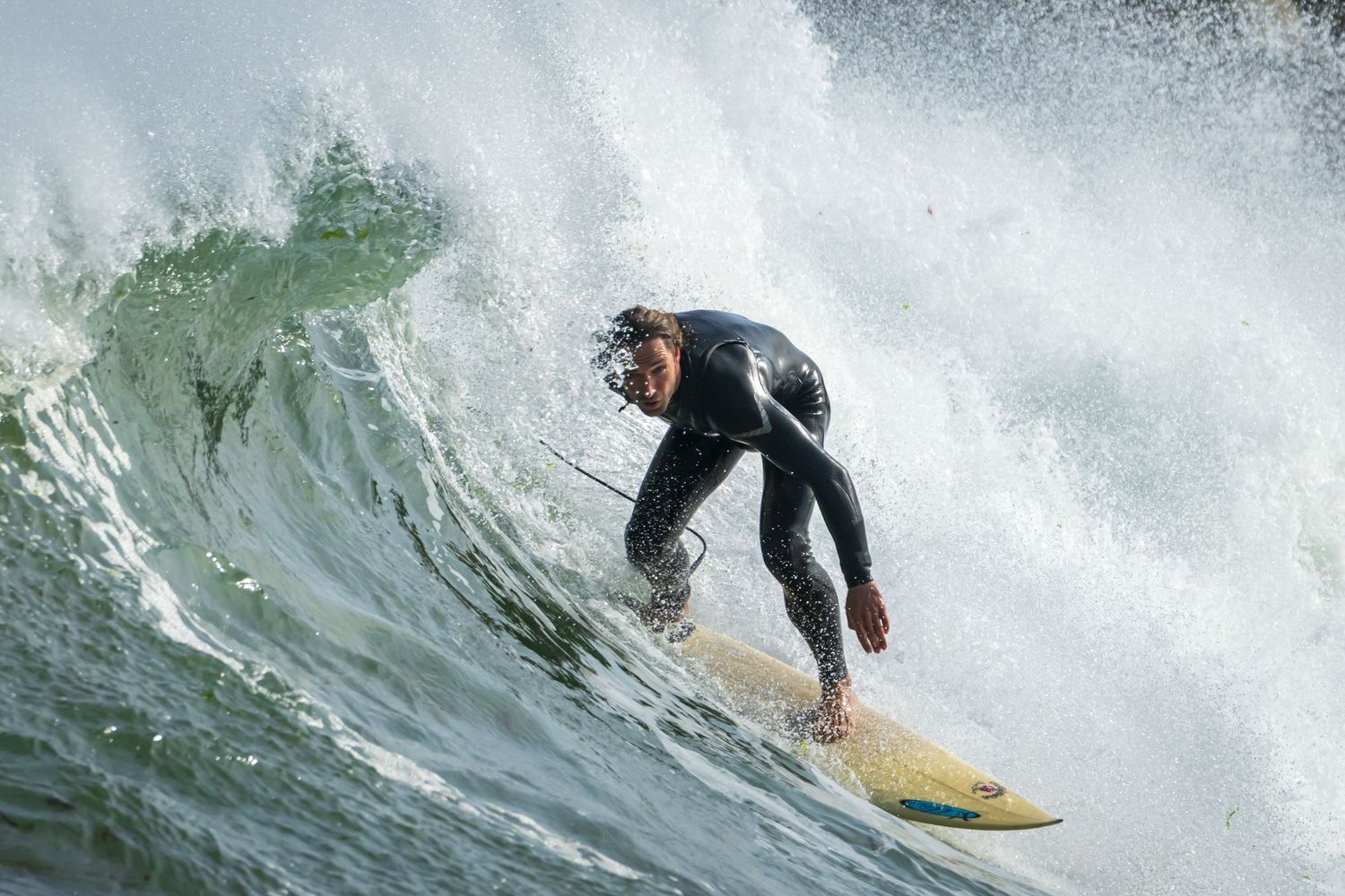 Surfer riding powerful ocean wave with dramatic water spray.