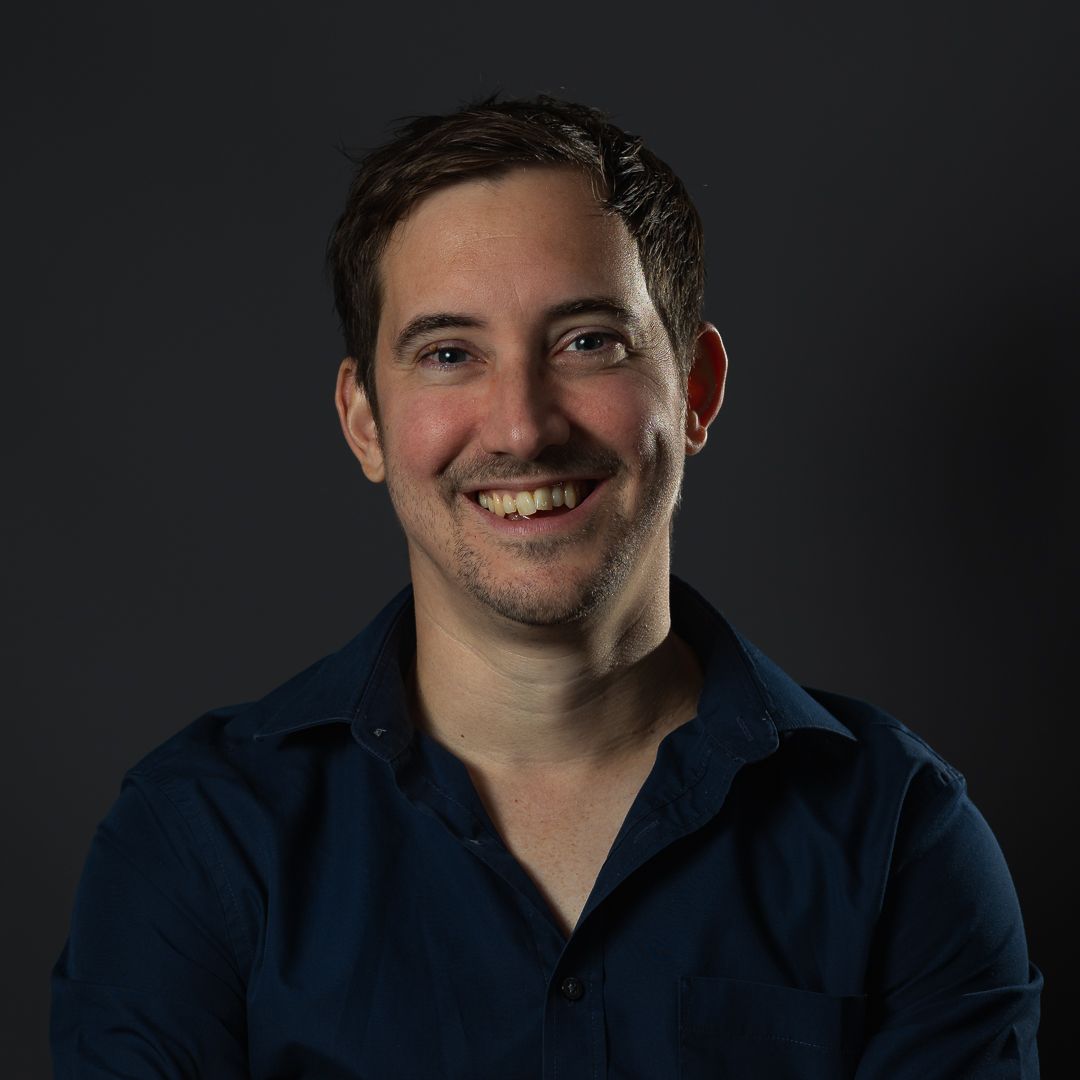 A profile photo of the website photographer, Ian Hartwell, smiling and wearing a navy blue shirt stood against a dark grey background.