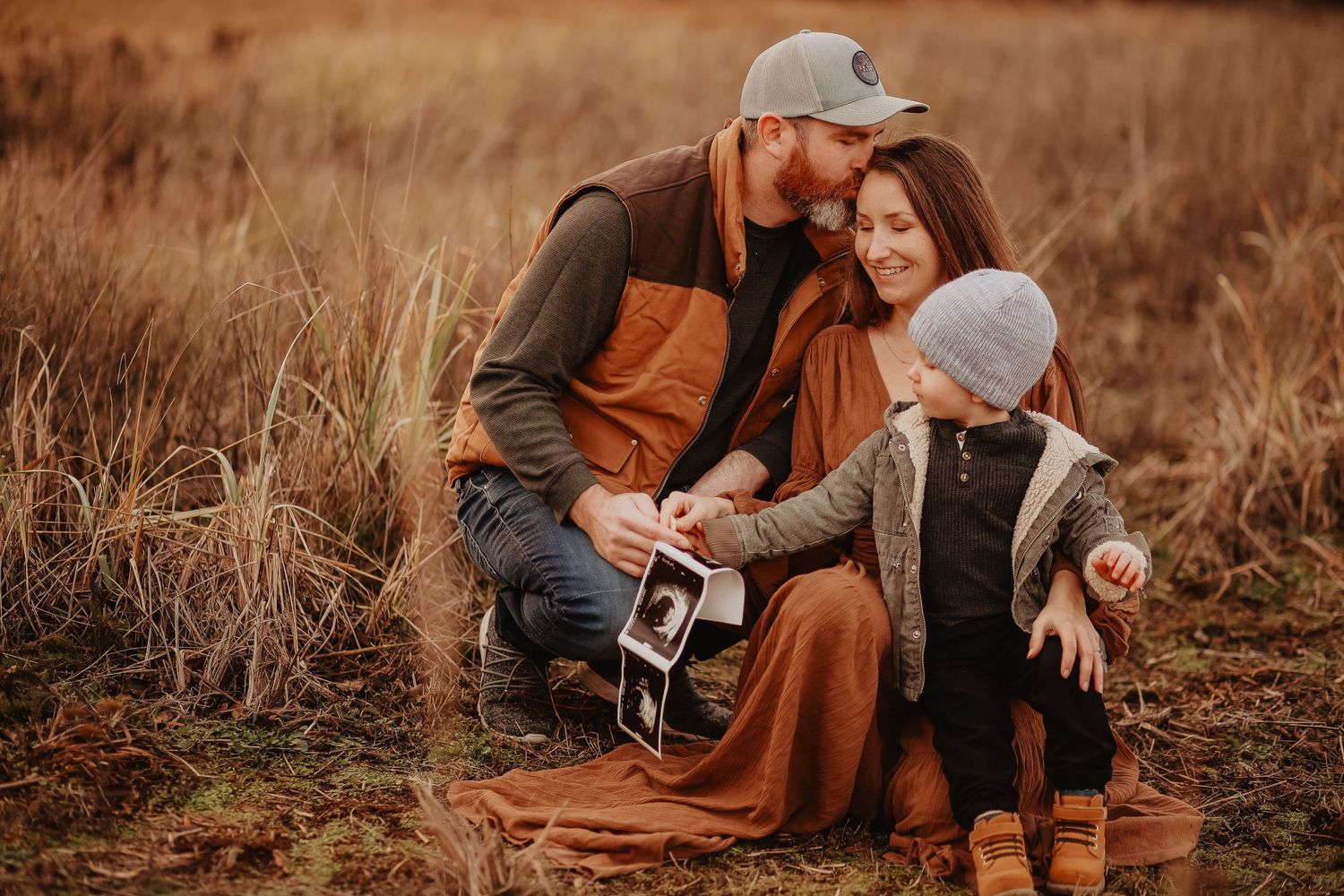 A couple poses intimately in a rustic outdoor setting with warm autumn tones.