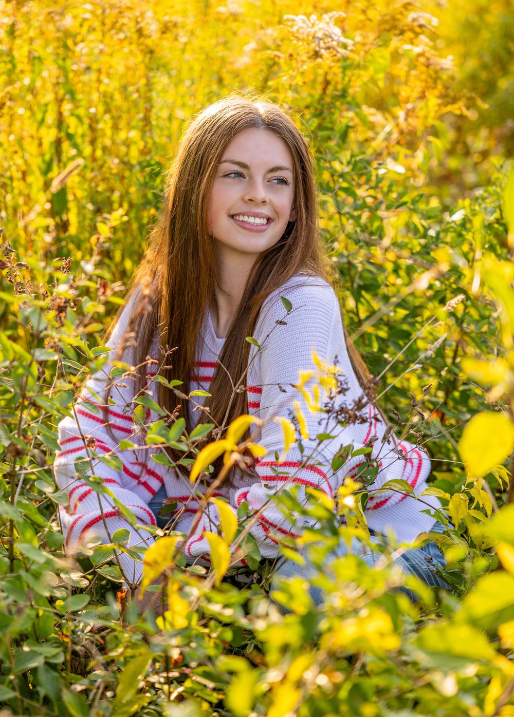 Autumn portrait in a field of yellow wildflowers wearing a patterned sweater.