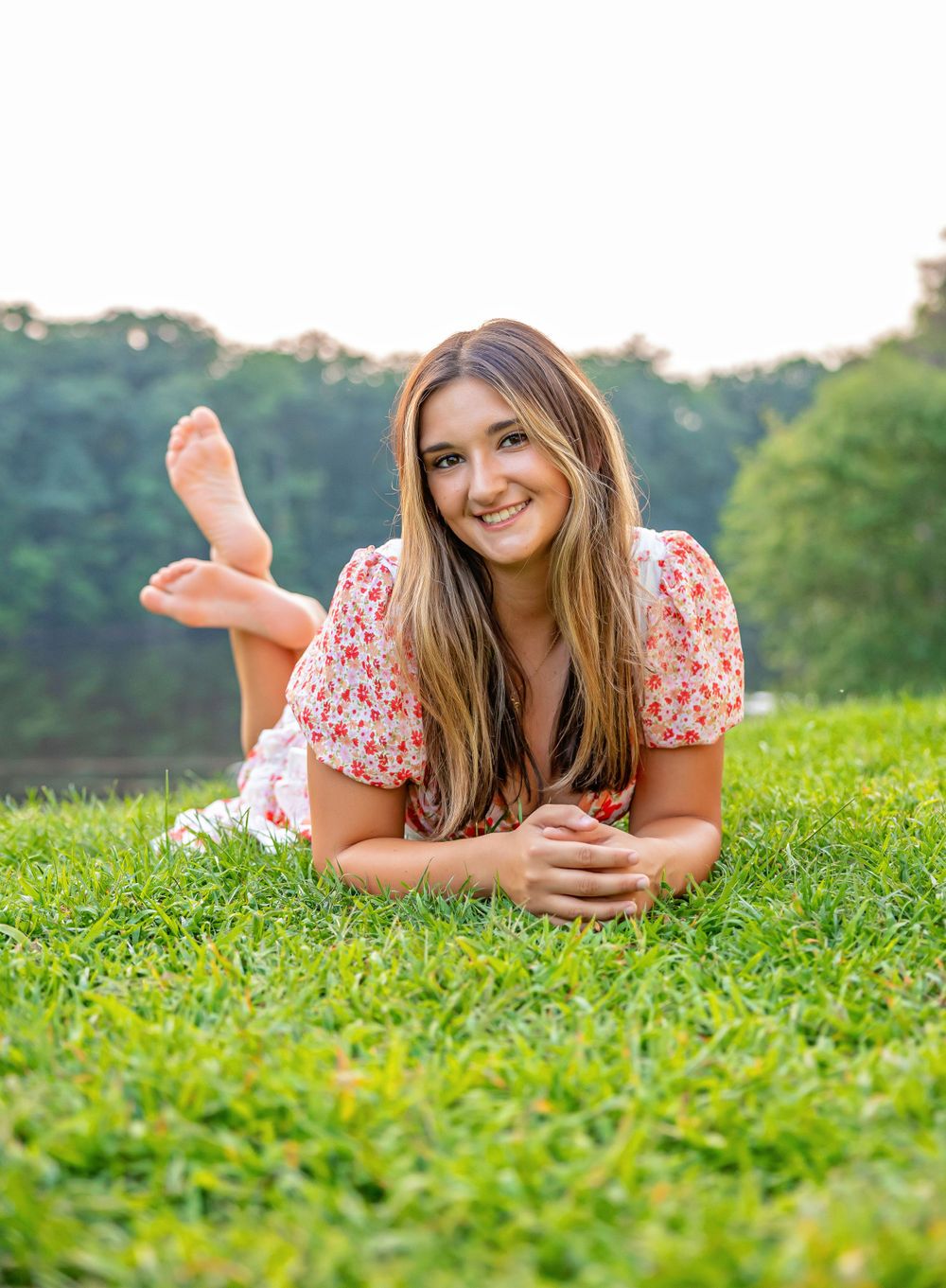 Summer portrait on grass wearing floral print dress in natural outdoor setting.