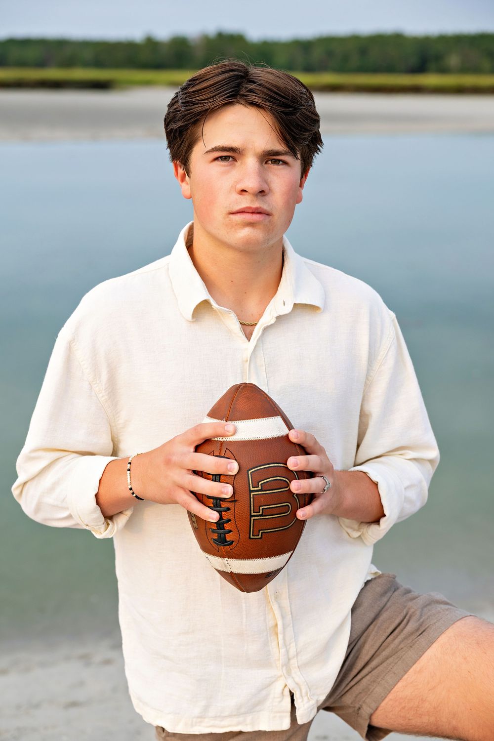 A person in a white shirt sits by a lake holding a football in a series of similar poses.