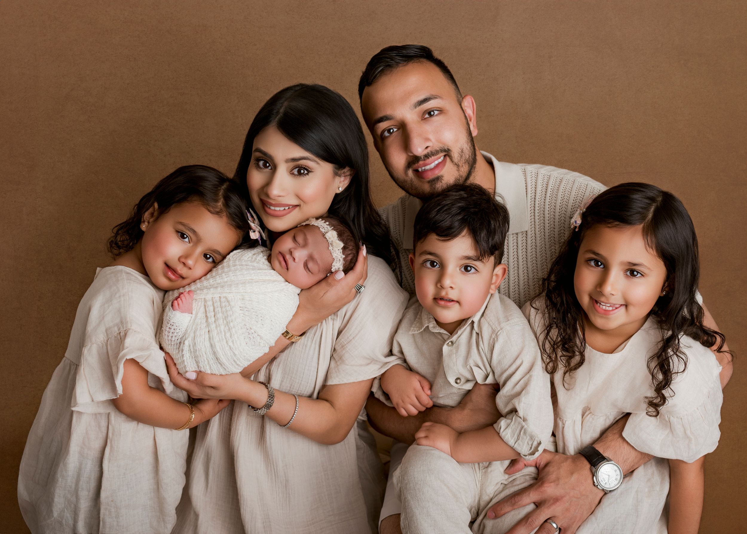 A series of sepia-toned family portrait photographs showing tender moments between parents and children in matching white outfits.