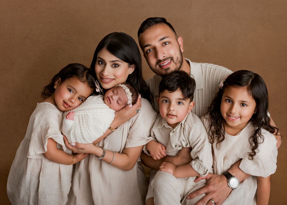 A series of sepia-toned family portrait photographs showing tender moments between parents and children in matching white outfits.