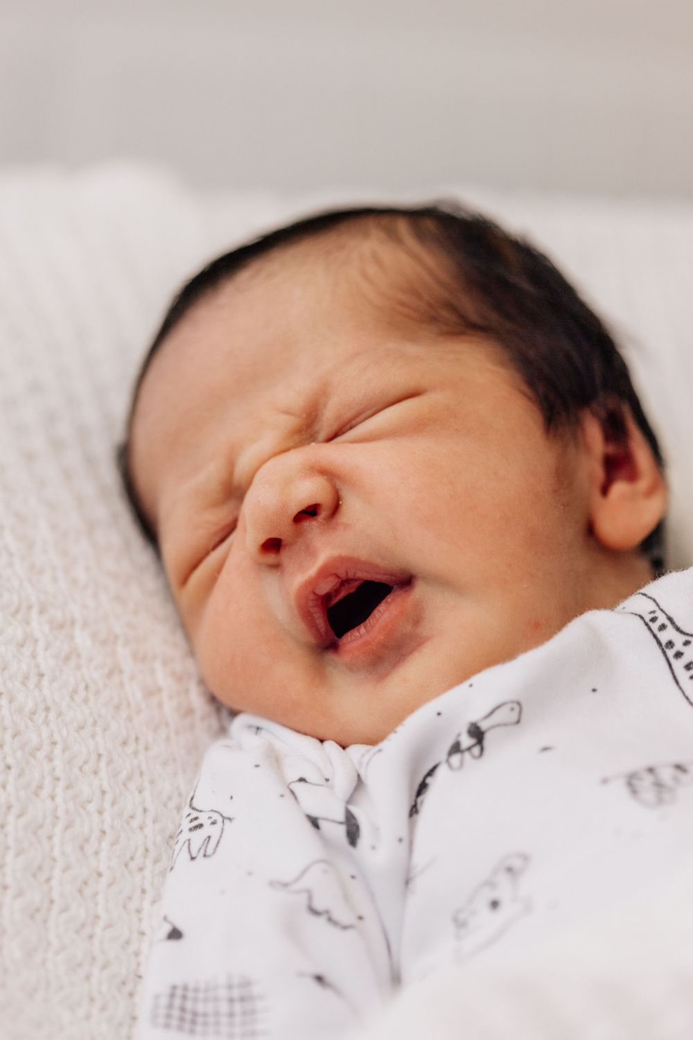 Detailed profile views of a peaceful sleeping newborn baby in white clothing.