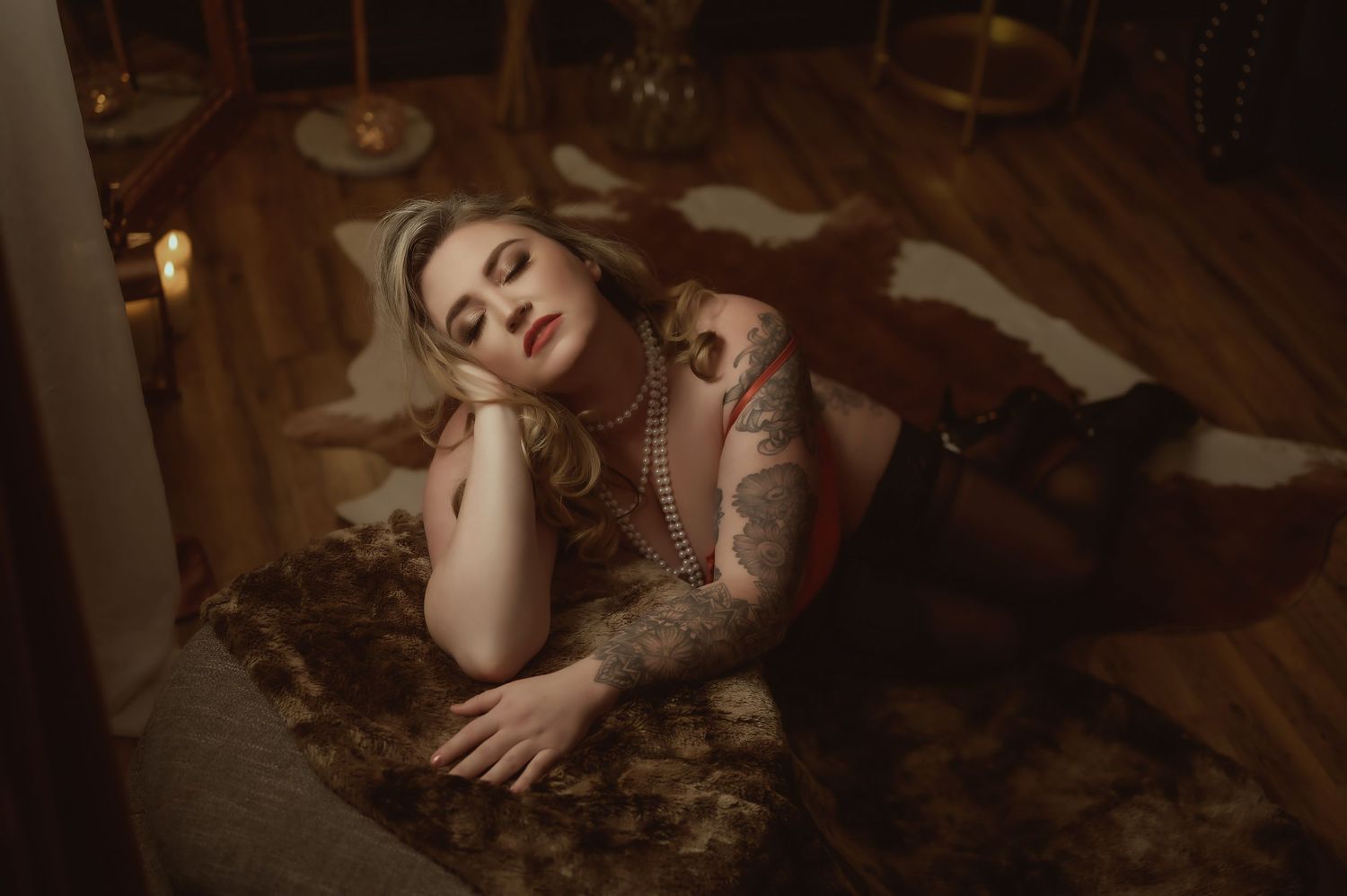 Atmospheric boudoir photo on hardwood floor with moody lighting and vintage decor.