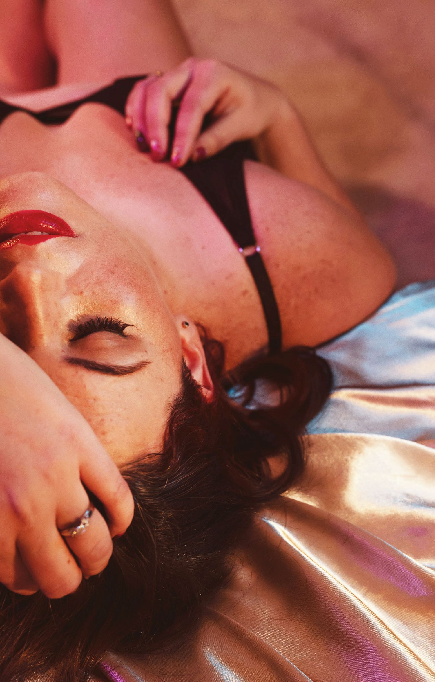 Intimate boudoir portrait with dramatic lighting showcasing dark lipstick and soft pose.