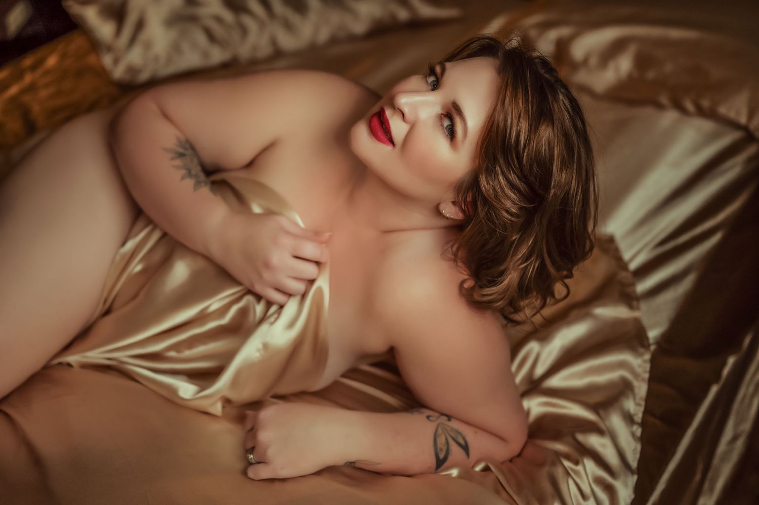 Intimate portrait on silk sheets with warm lighting and natural poses.