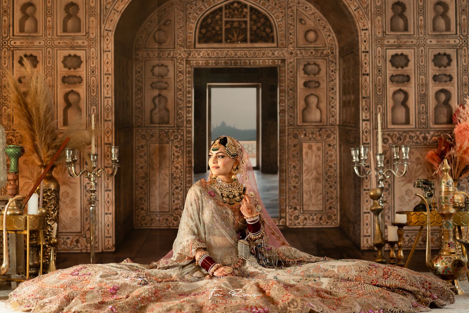 Ornate Indian-Wedding inspired bride photo wearing designer-wear and intricate wall carvings in warm golden tones.