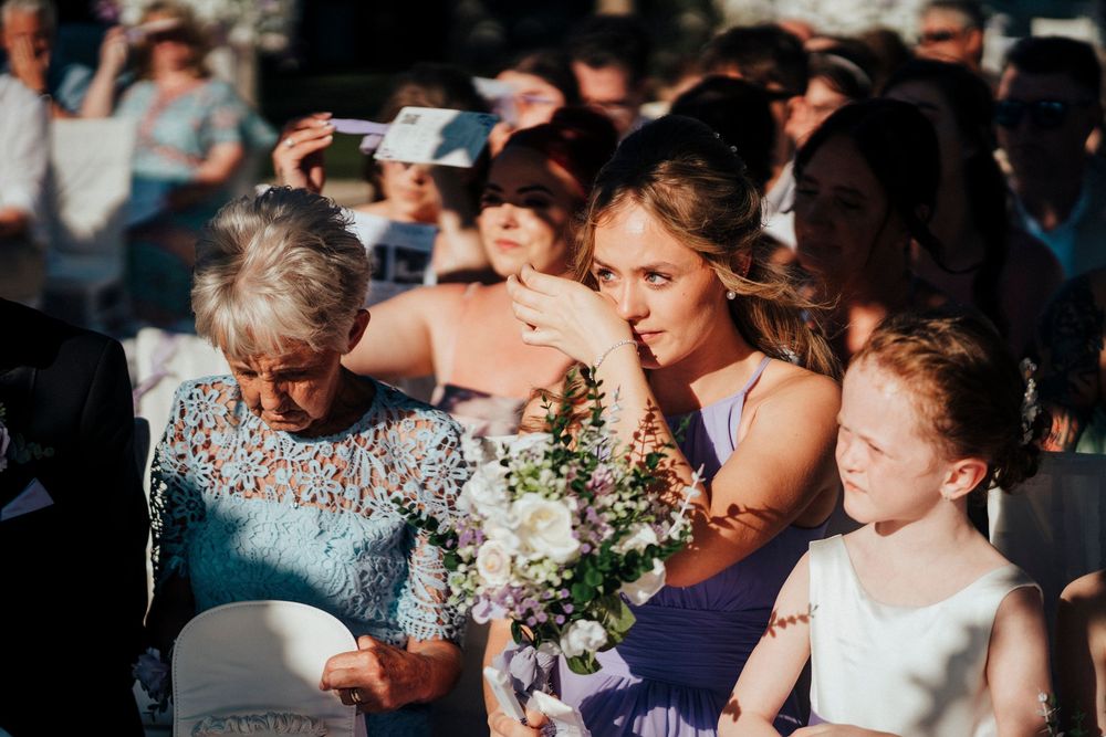 Wedding guests sharing emotional moments during a celebration with bouquets and formal attire.
