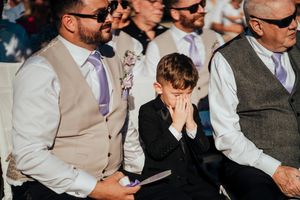 Wedding guests seated in formal attire watching the ceremony with sunlight streaming in.