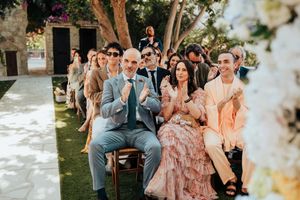 Wedding party celebrates outdoors in a garden setting with floral decorations and natural lighting.