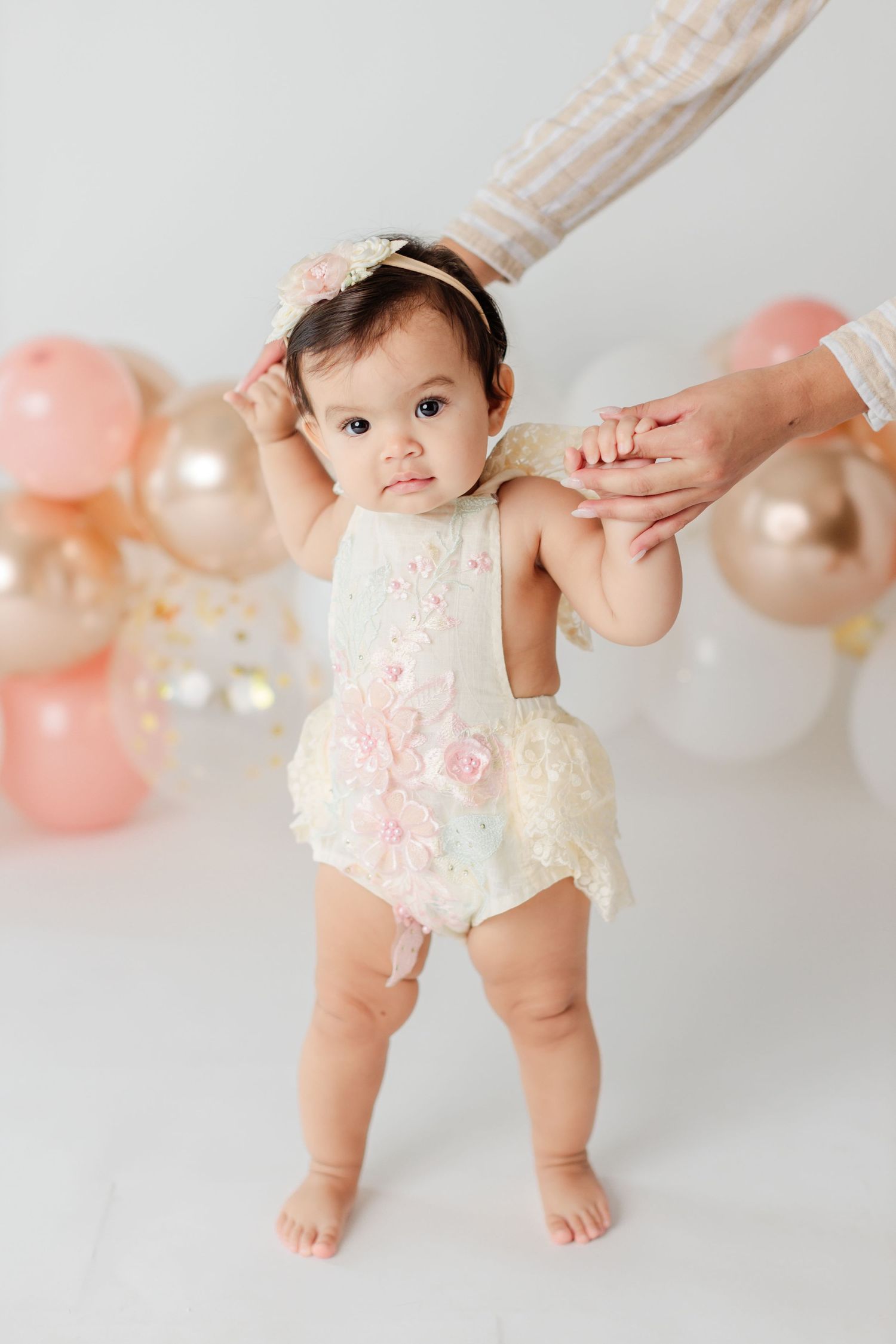 One year standing up with balloons in the background old during cake smash session