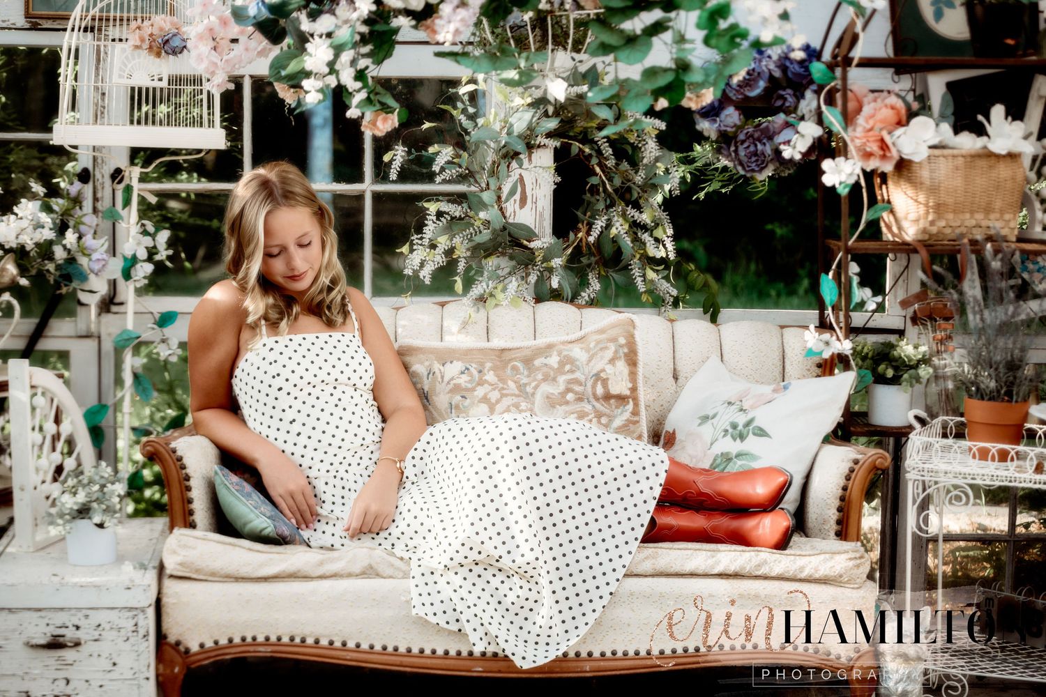 A vintage-style photo shoot featuring a polka dot dress on an antique chaise lounge with floral decorations.